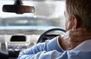 Close-up of male driver suffering from whiplash, pressing hand to his neck