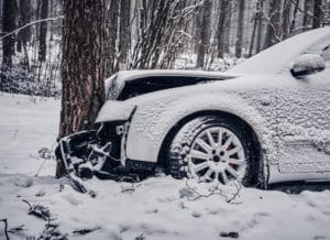 snow covered car crashed into tree