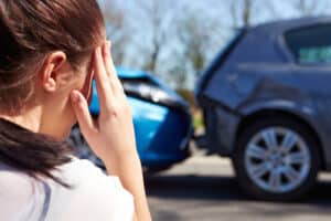 Close-up of driver touching head while looking at car accident scene