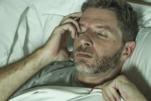 Close-up of distressed man lying in bed