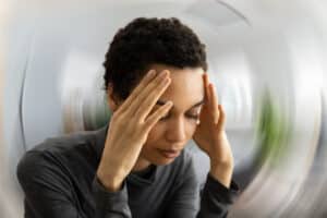 Young woman holding hands to head in distress, blurry background