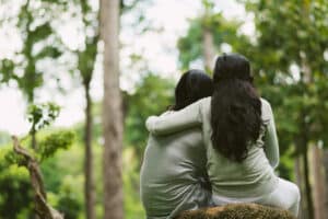 Two friends sitting outside, supportive arm around shoulders