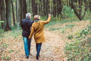 Older couple walking in woods in autumn