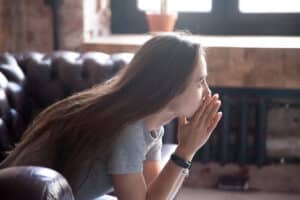Anxious young woman sitting on couch at home