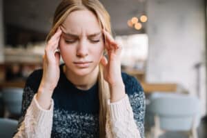 Young woman holding hands to head, headache